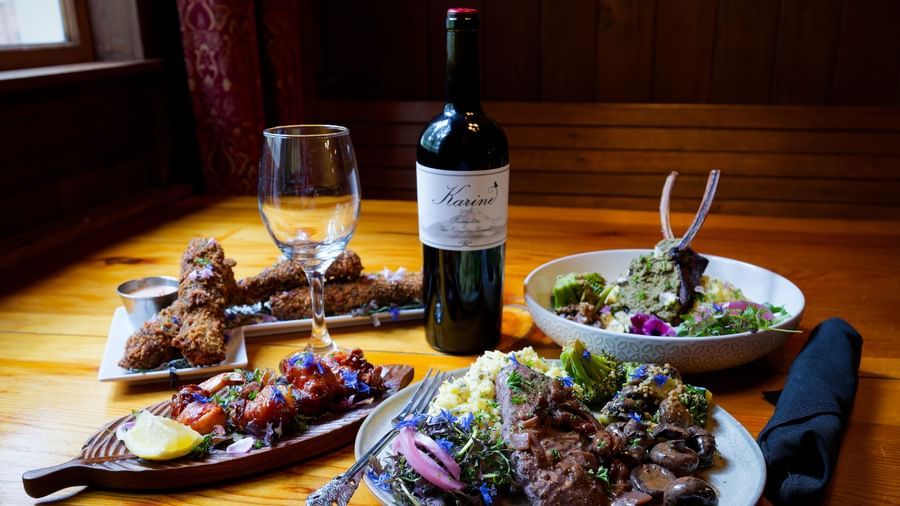 Elegant dinner setting with wine, salad, grilled meat, and pasta in a cozy dining room at Narrow Gauge Inn.
