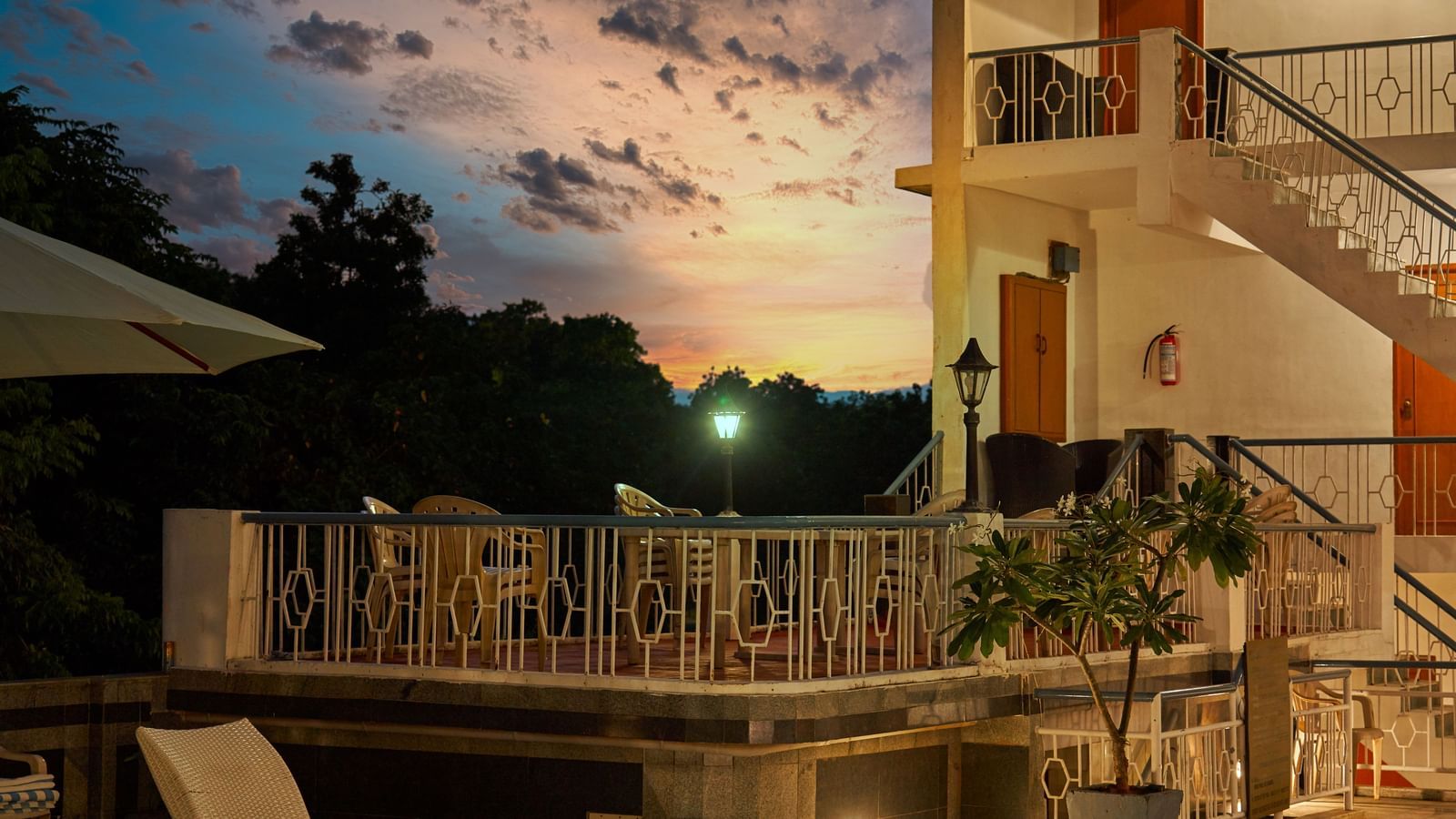 The exterior of Hotel Mamallaa Heritage and its pool area illuminated at dusk or night, creating a warm and inviting ambience.