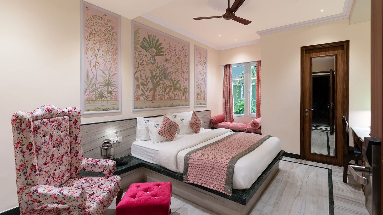 A spacious bedroom at Panna Vilas Palace, complete with a wooden table, cushioned furniture, warm lighting, and a large window