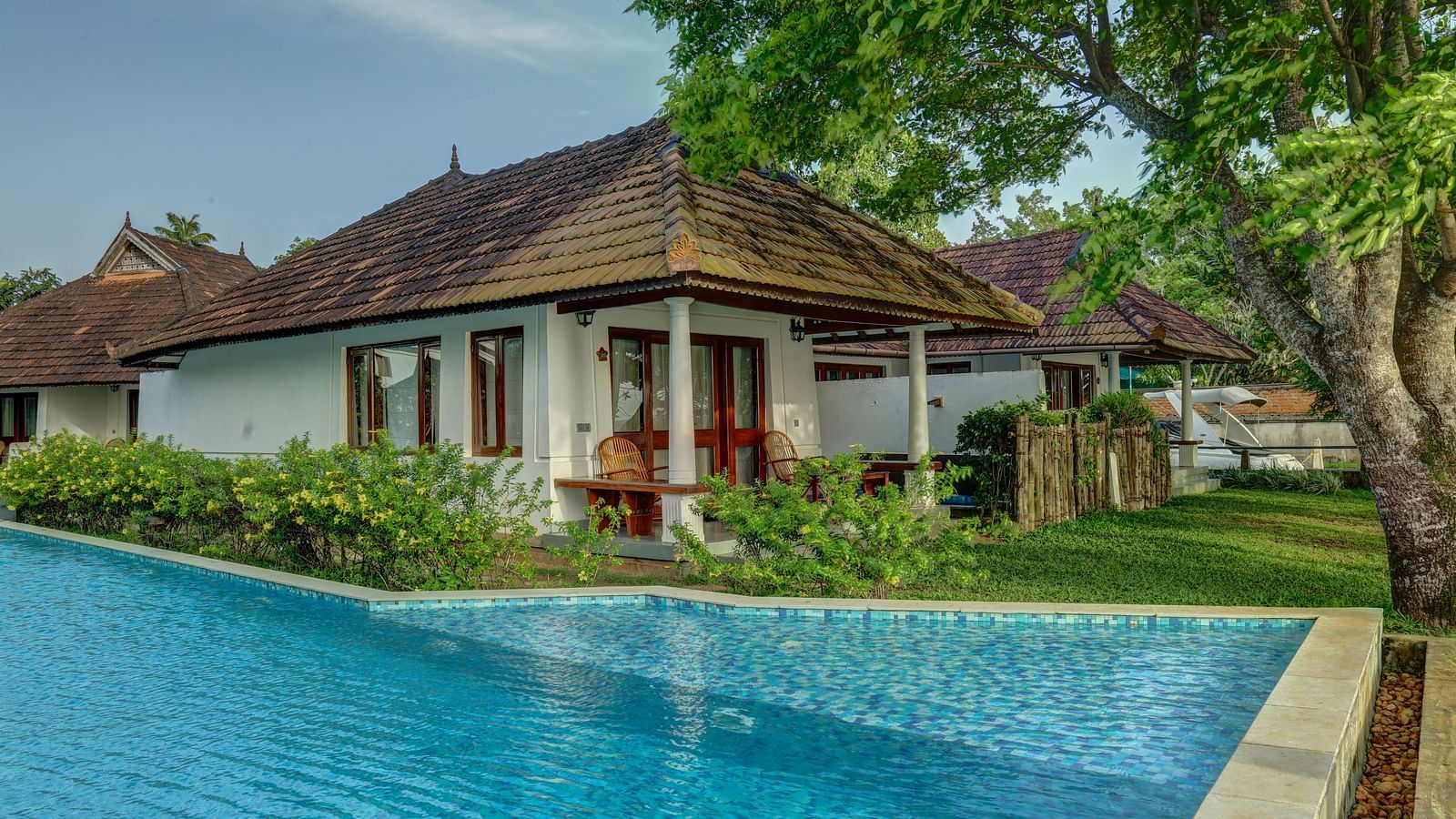 A cluster of cottages nestled around a central swimming pool - Rhythm Kumarakom