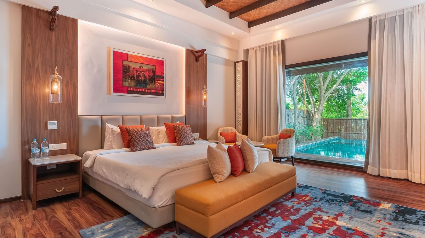A king size bed with ottoman and a large floor to window ceiling at Ananta Villa - The Ananta Udaipur