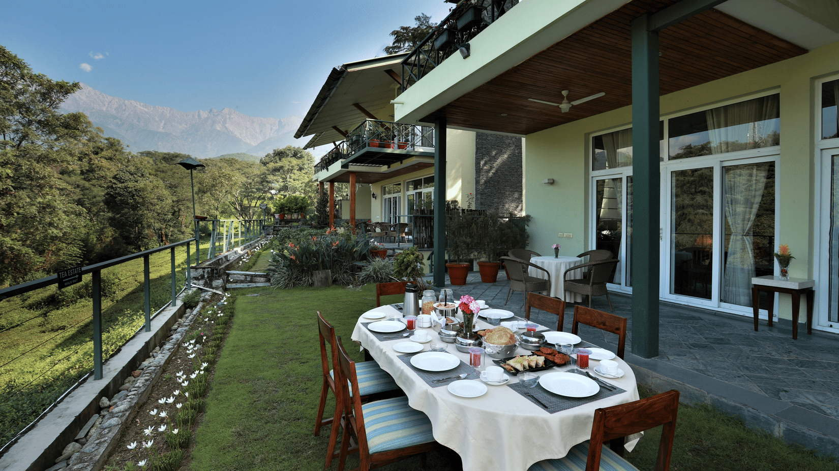 Scenic outdoor dining area with a breakfast spread overlooking lush greenery and mountains.