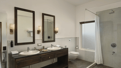 Bathroom of Plunge Pool Suite in Fateh Safari Suites featuring sinks with faucet and mirror attached on the walls, shower screen, and other toiletries in different corner of the room.