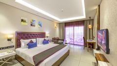 A hotel room in candolim featuring a king size bed, a wall-mounted television, and a balcony - Golden Tulip, Candolim, Goa