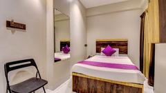 Classic Single Room with bed, purple accent runner, full-length mirror and folding chair at VITS Select Kharadi Pune