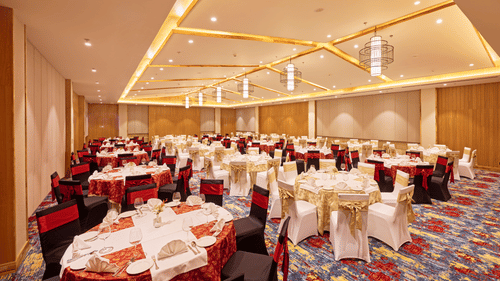 Banquet hall setup with red and white chair covers and decorative lighting - Royal Tulip, Chitwan