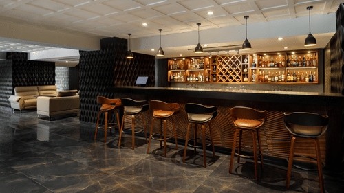 The well-appointed bar at Royal Tulip, Kathmandu, with bar stools, a marble floor, and bottles displayed.