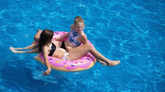 children sitting on a pool float inside the swimming pool