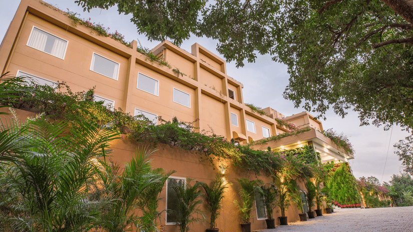 The facade of Lalitha Grand, featuring plants infront of the building.