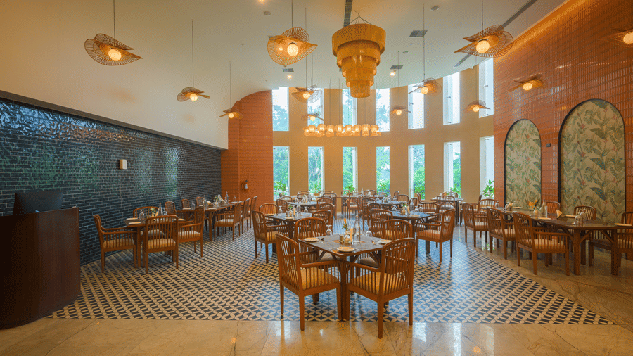 Restaurant dining area with wooden tables and chairs, pendant lights, decorative walls and large windows.