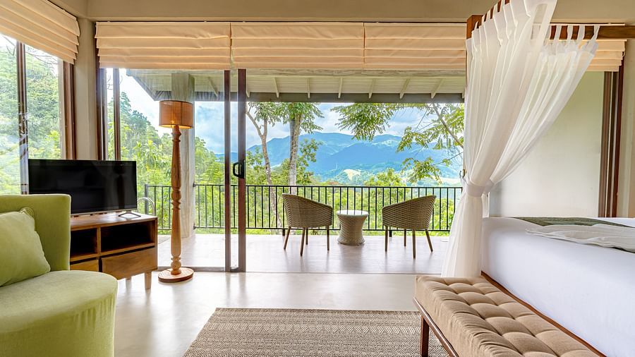 A full view of a room with a TV, bed and a balcony with two chairs | Celestial Hills - Villas & Suites by the Clarks, Kandy