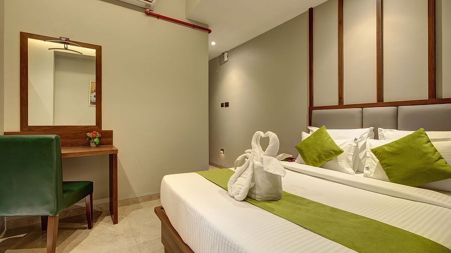 A double bed with a side table next to it inside Classic AC Room - Fortune House, Magarpatta