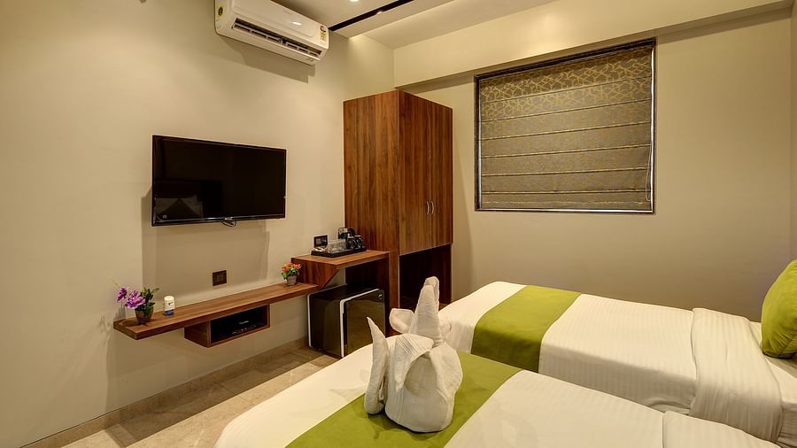 Twin bed with dove towels on it inside Premium Twin Sharing Room - Fortune House, Magarpatta