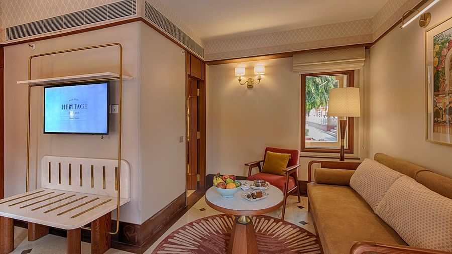 Cosy living area featuring a flat-screen TV, round coffee table, comfortable sofa, and warm ambient lighting, with a scenic garden view