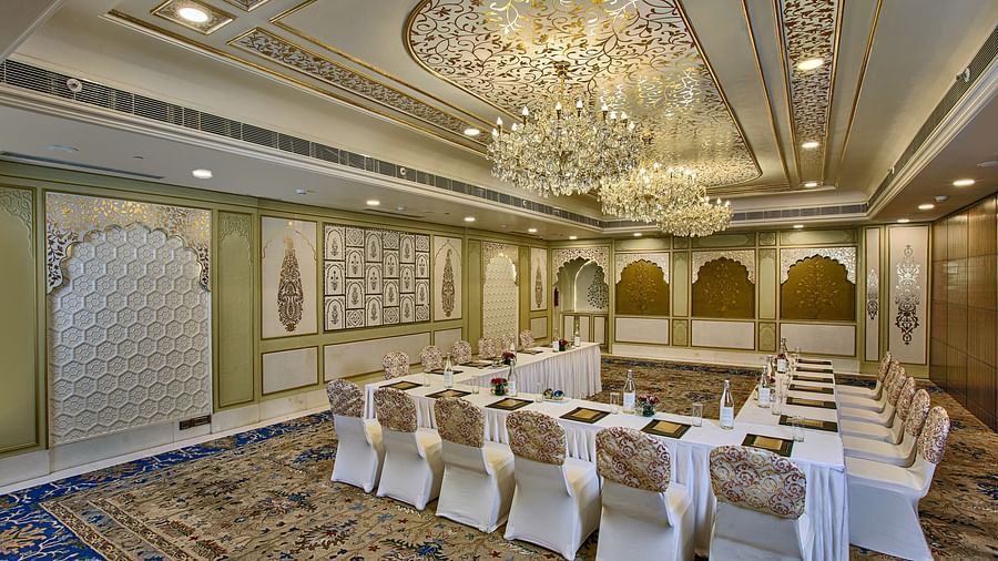 Elegant meeting room with a U-shaped table, ornate ceiling, chandeliers, and patterned carpet - Heritage Village Resorts & Spa.