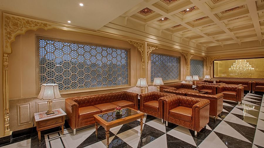 A beautifully designed lounge with plush leather seating, intricate lattice windows, and soft ambient lighting - Heritage Village Resorts & Spa, Manesar