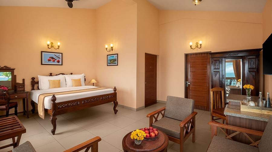 A seating area in a room in Sindhudurg with a seating area and a plush bed on a wooden frame bed - Highland Sarovar Portico, Sindhudurg