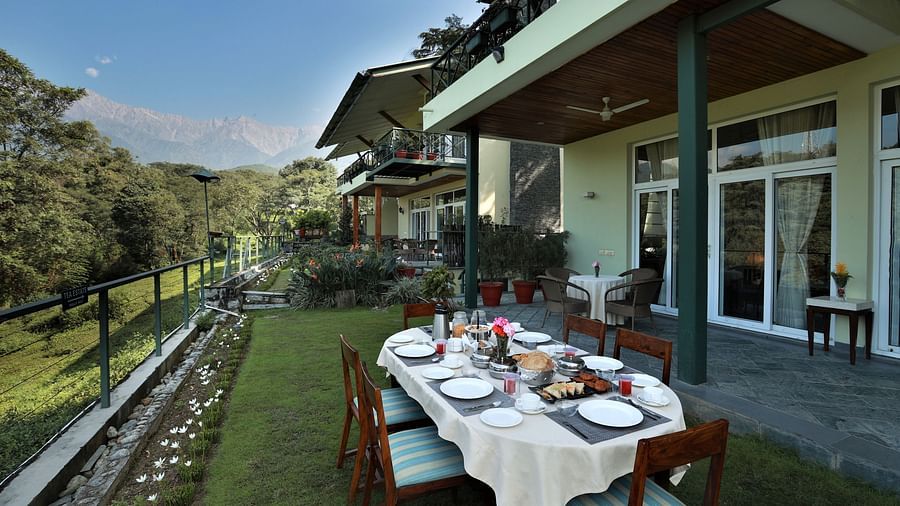 Scenic outdoor dining area with a breakfast spread overlooking lush greenery and mountains.