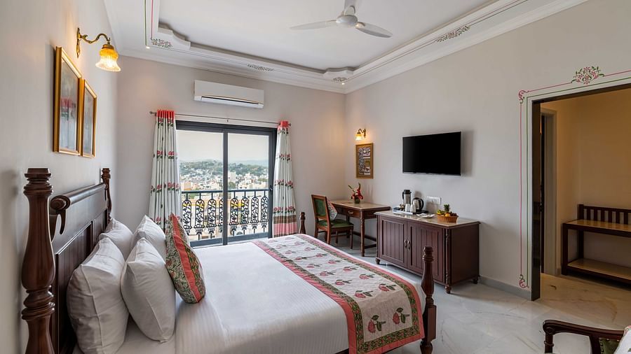 An overview of the suite with a king bed, tv and balcony at Superior Room - Maan Vilas by Stone Wood, Udaipur