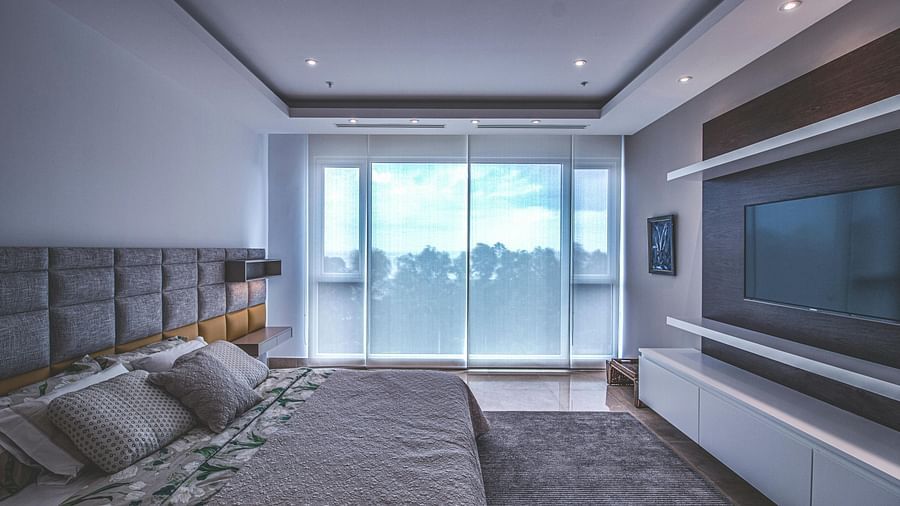 A spacious bedroom featuring a king size bed, soft lighting, and a large window with natural light streaming in.