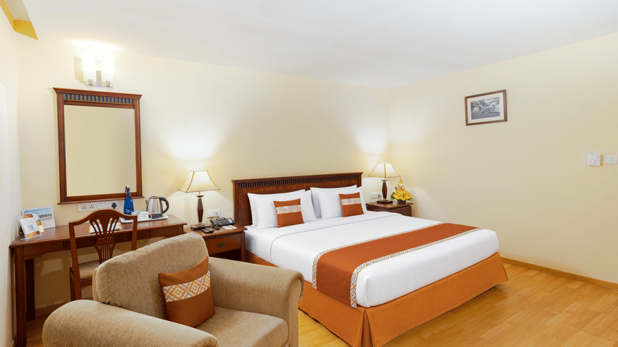 A room with a large bed, spreads, pillows, a sofa, a mirror, and lights. | MGM Mark Whitefield