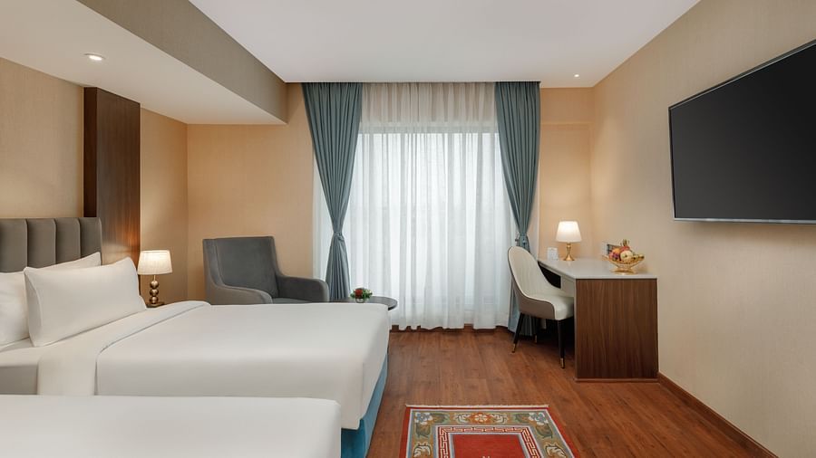 Spacious twin room at Royal Tulip, Kathmandu, with a desk, flat-screen TV, and pleasant natural light.