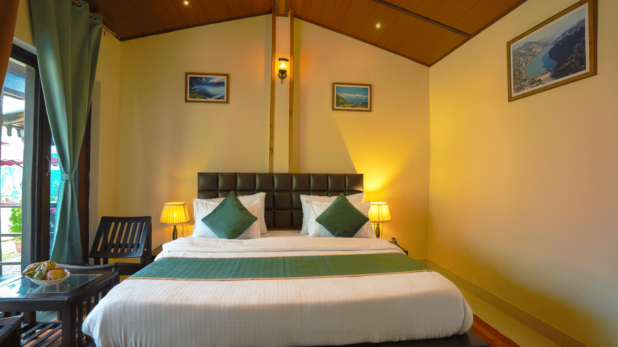 A bedroom featuring a bed, 2 chairs and wall paintings arranged in a proportionate manner | Sol Glow Resort, Nainital