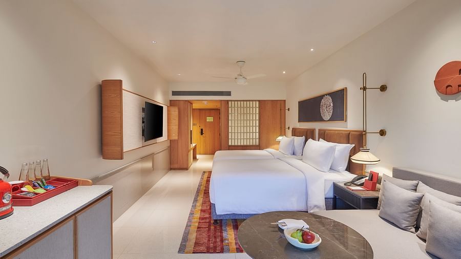 A well lit bedroom with a king bed, TV, table and sofa with white walls at The Dukes Retreat.