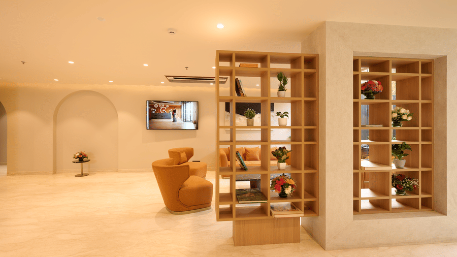 The lobby lounge at Tulip Inn Gurugram featuring tan leather armchairs and a wooden lattice partition wall with decorative plants.
