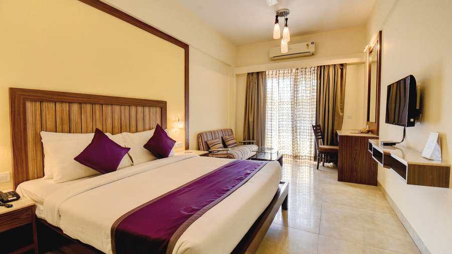 Spacious executive room with king-size bed, purple accents, and balcony at VITS Lonavala.