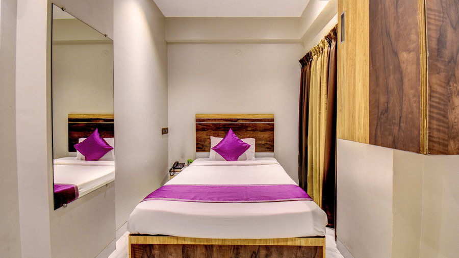 Classic Single Room with bed, purple linen, wooden headboard and full-length mirror reflection at VITS Select Kharadi Pune