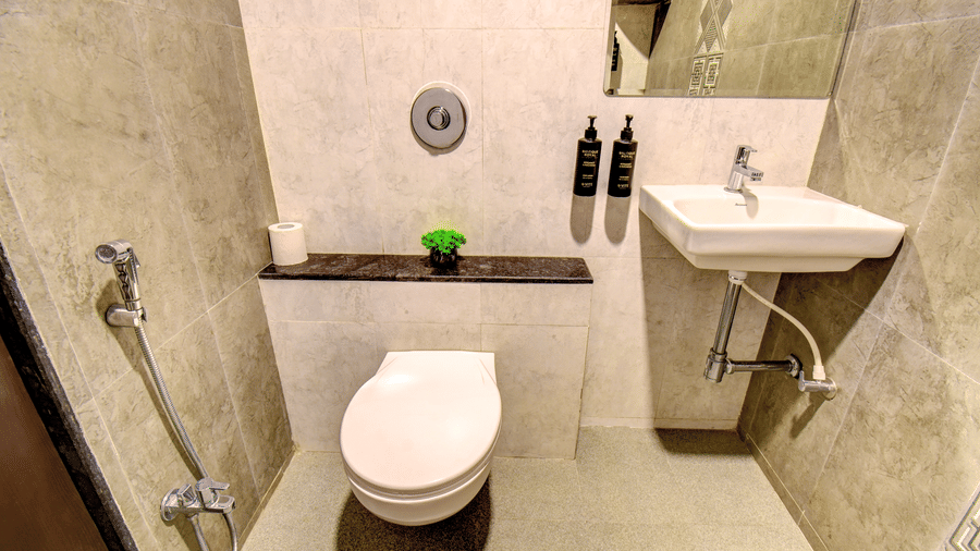 Deluxe Room bathroom with grey marble tiles, wall-mounted toilet, pedestal basin and premium toiletries at VITS Select Kharadi Pune