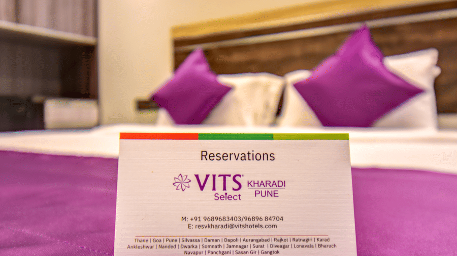 Super Deluxe Room king bed with purple accent runner featuring a reservation card at VITS Select Kharadi, Pune