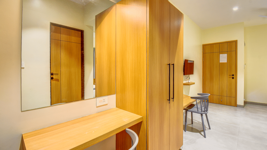 Dressing area with mirror, desk, stool, and wooden wardrobe at VITS Select Nashik Hotels & Resorts.