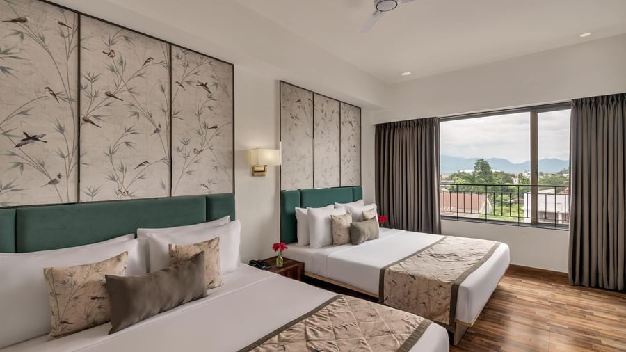 Twin bedroom at Voyage Milestone Hotel and Banquet with large windows and drapes.