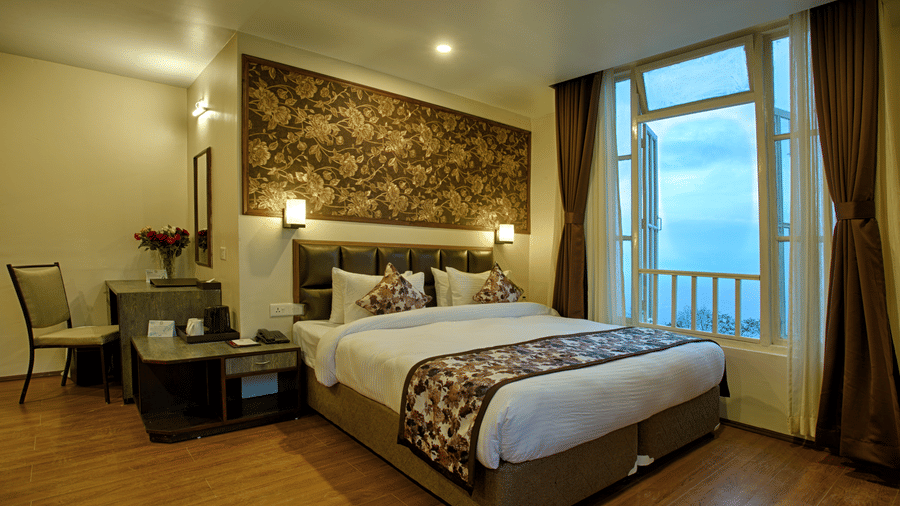 Elegant hotel room at Voyage The Aryan Regency with ornate floral wallpaper, comfortable bed, work desk, and large windows overlooking the exterior