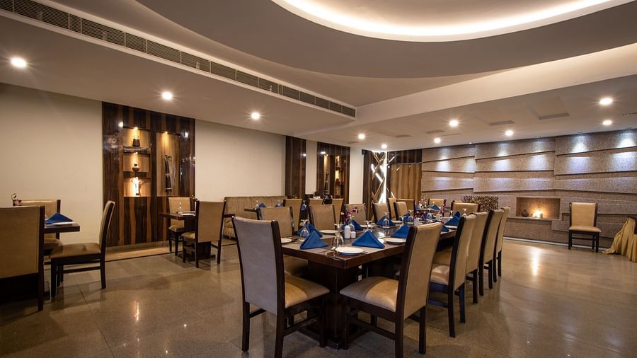 The interiors of the restaurant feature elegant chair-table arrangements - Wedlock Greens Hotel Resorts Dhanbad