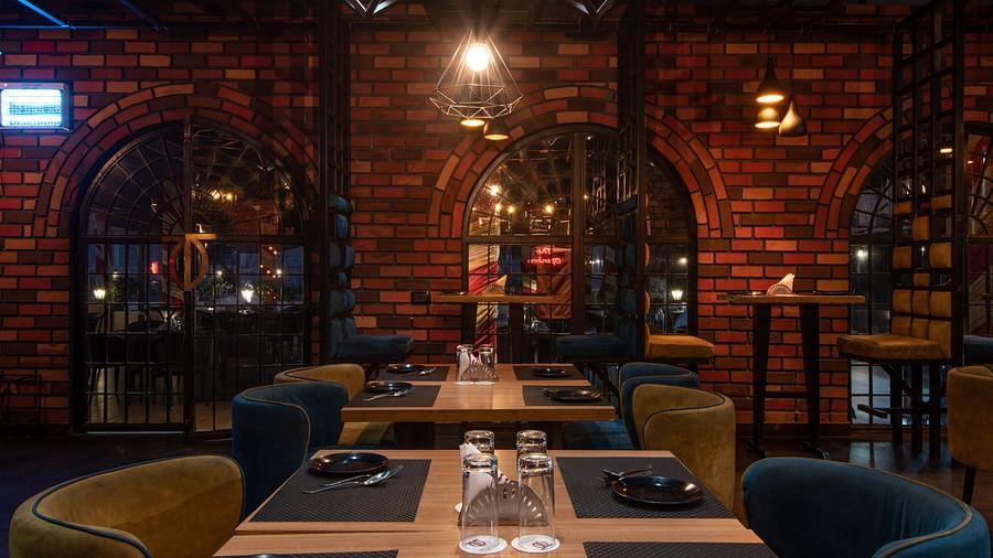 A close-up shot of a dining table surrounded by brick walls - Wedlock Greens Hotel Resorts Dhanbad