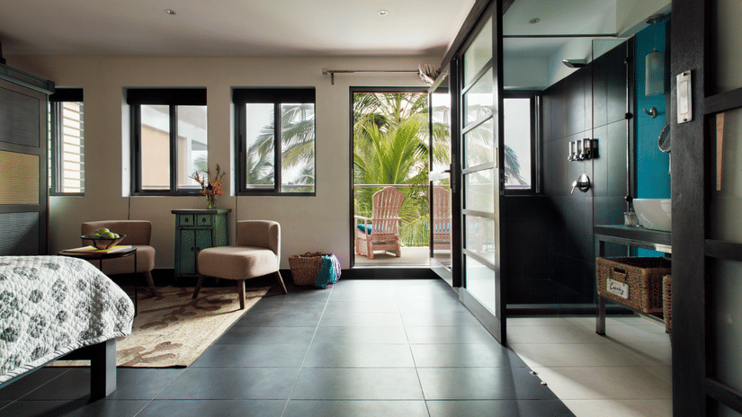 A brightly lit room at Owl and the Pussycat Hotel In Galle with a sitting area and windows overlooking greenery.