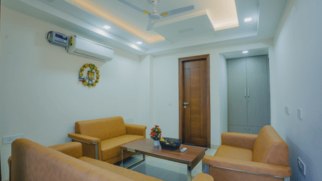 Lounge area of Lime Tree Hotels & Service Apartment Private Limited featuring orange armchairs and a view towards the corridor.
