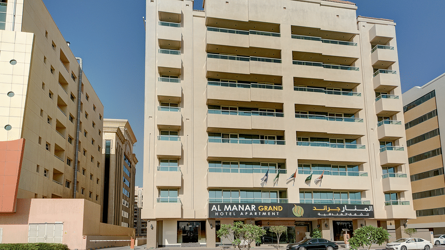 The exterior of a multi-storey sand-coloured hotel building against a clear blue sky in a city - Al Manar Grand Hotel Apartment, Bur Dubai