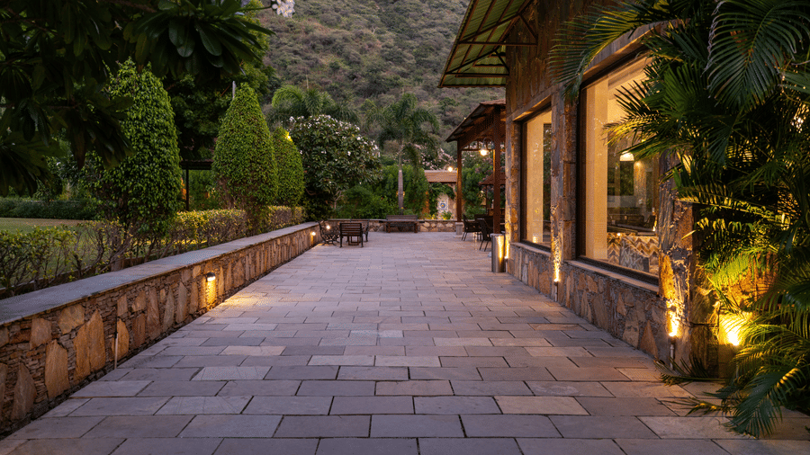 A paved outdoor walkway illuminated by low floor lights leading through the resort gardens | Anandam Jungle Retreat Resort, Udaipur
