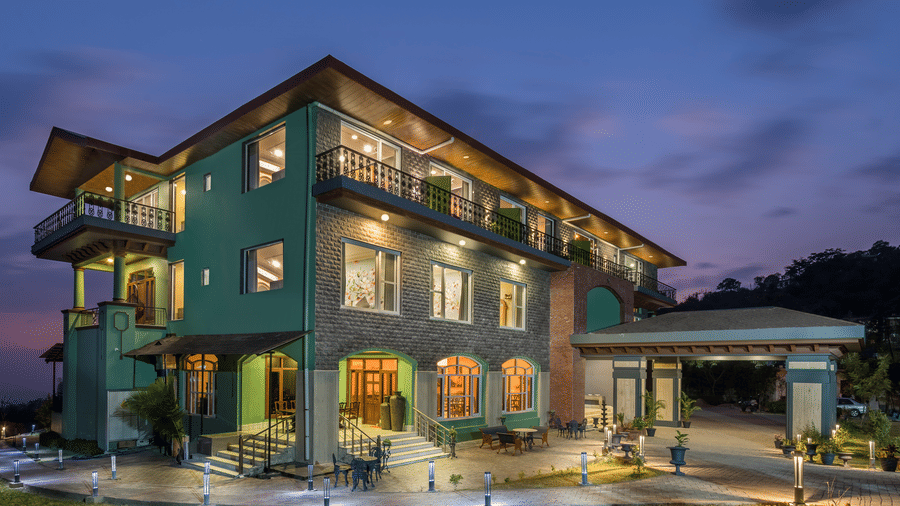Exterior of Atman, Dharamshala during blue hour with hills in the background.