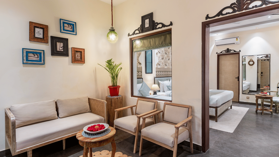 A living area of a villa at Beelwa Palace, Jaipur, featuring a seating space with sofas and a centre table by the doorway to the bedroom