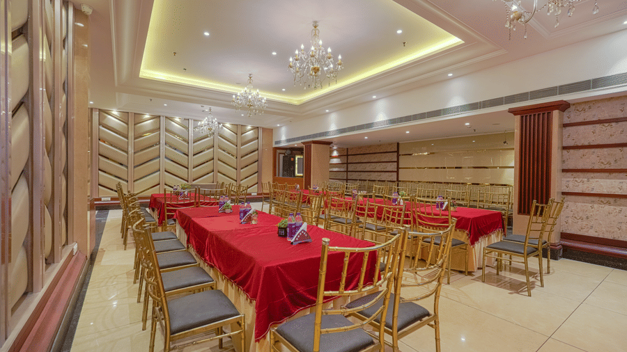 A luxury private dining or conference room with a long table covered in a red cloth, surrounded by gold and grey chairs at BluSalzz Select City Centre, Amritsar.