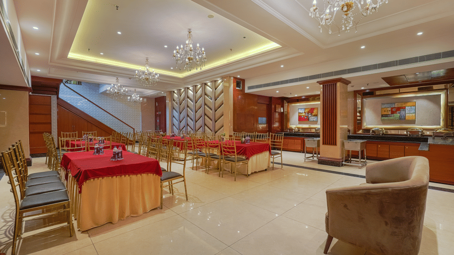 A perspective shot showing the dining room leading to a lower lounge area, highlighting the rich decor and ceiling lighting at BluSalzz Select City Centre, Amritsar.