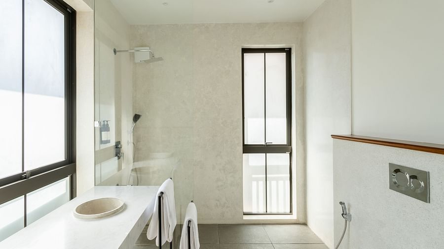A contemporary bathroom with a glass-enclosed shower, a sleek toilet, and a window overlooking the outdoors - BluSalzz Villas - Alocassia, Anjuna