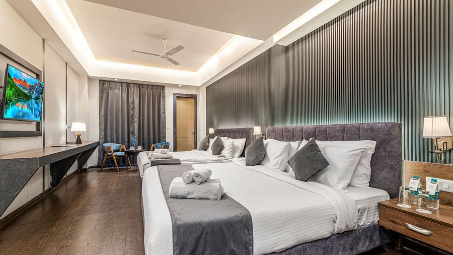 A mirror shot of a room at DLS Ganga Bliss, Haridwar with two king size beds facing a flat screen TV mounted on a wall