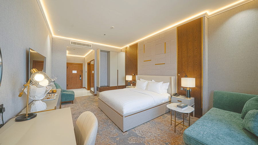 Wide view of the Standard King Room at Grand Iva Hotel, ABha, featuring a plush double bed, wiht bedside tables facing the wall-mounted TV.