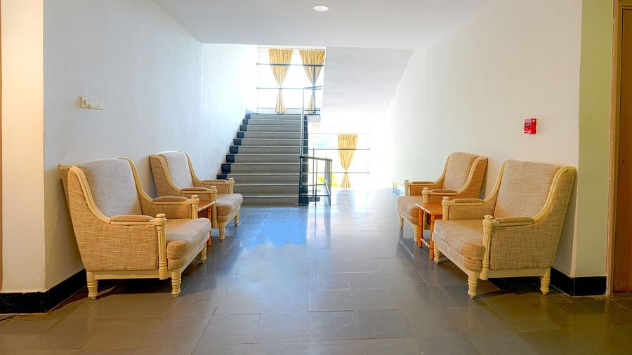 A hotel's lobby area with armchairs and a staircase in the background at Greens Inn - Inviting Lobby in Ramoji Film City.